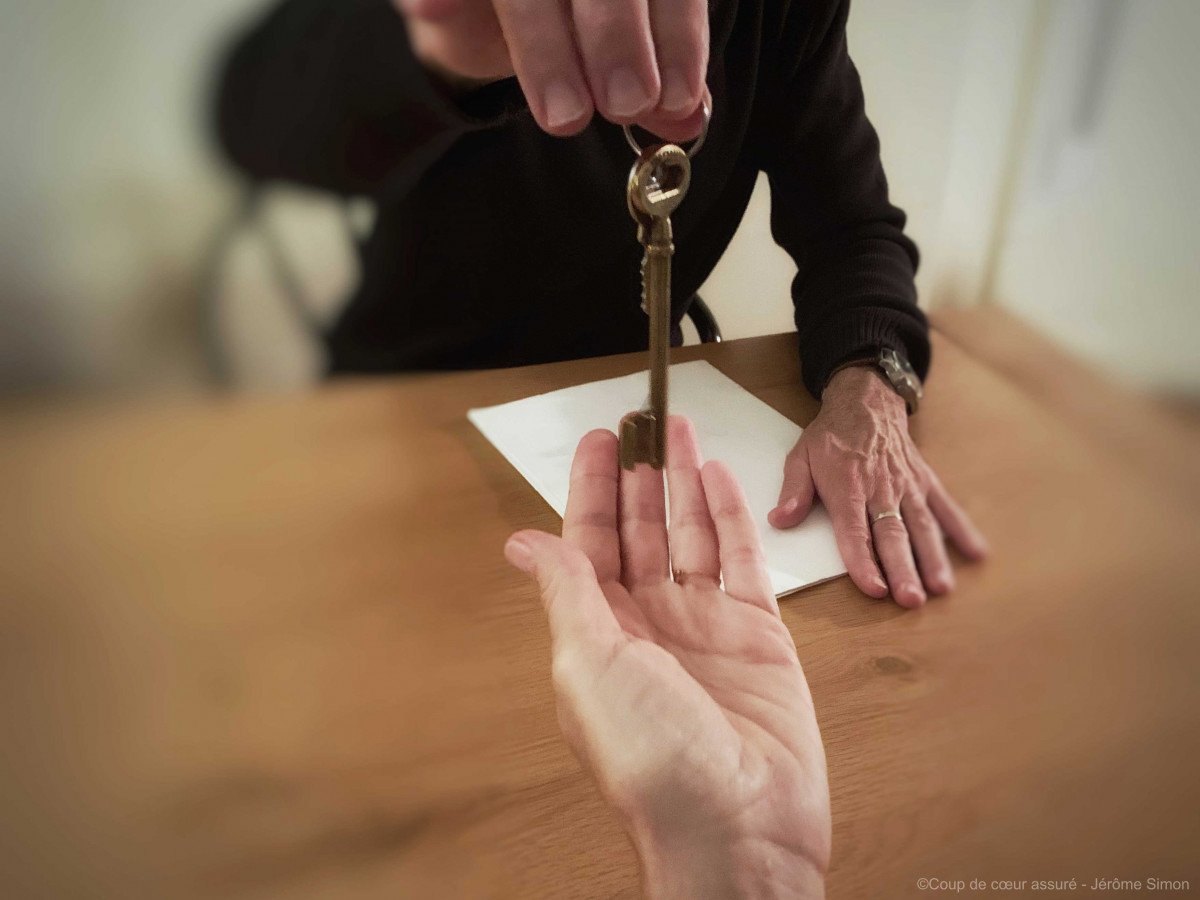 Un homme main sur un titre de propriété tend les clés d'un bien immobilier
